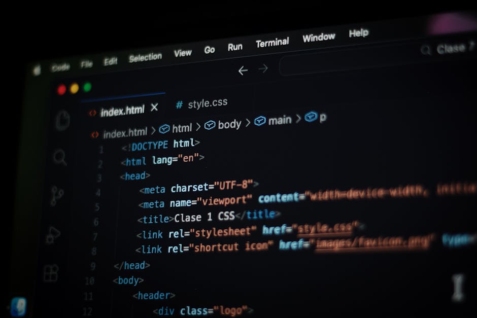Close-up view of a computer screen displaying colourful lines of code on a dark background, with the code appearing slightly blurred. The screen shows various programming elements including text in re